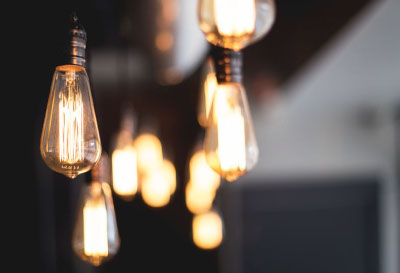 A collection of light bulbs with no shades hanging from ceiling
